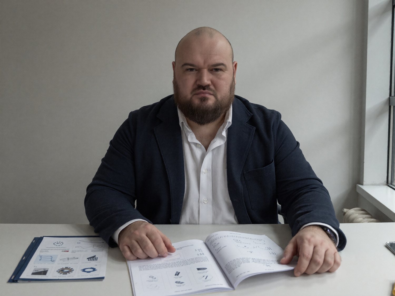 Oleg Freidkin reviewing printed product catalogues at a desk